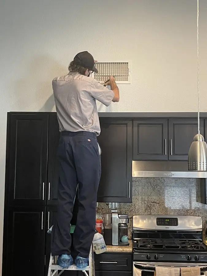 Technician inspecting an air vent during HVAC service in Collingdale